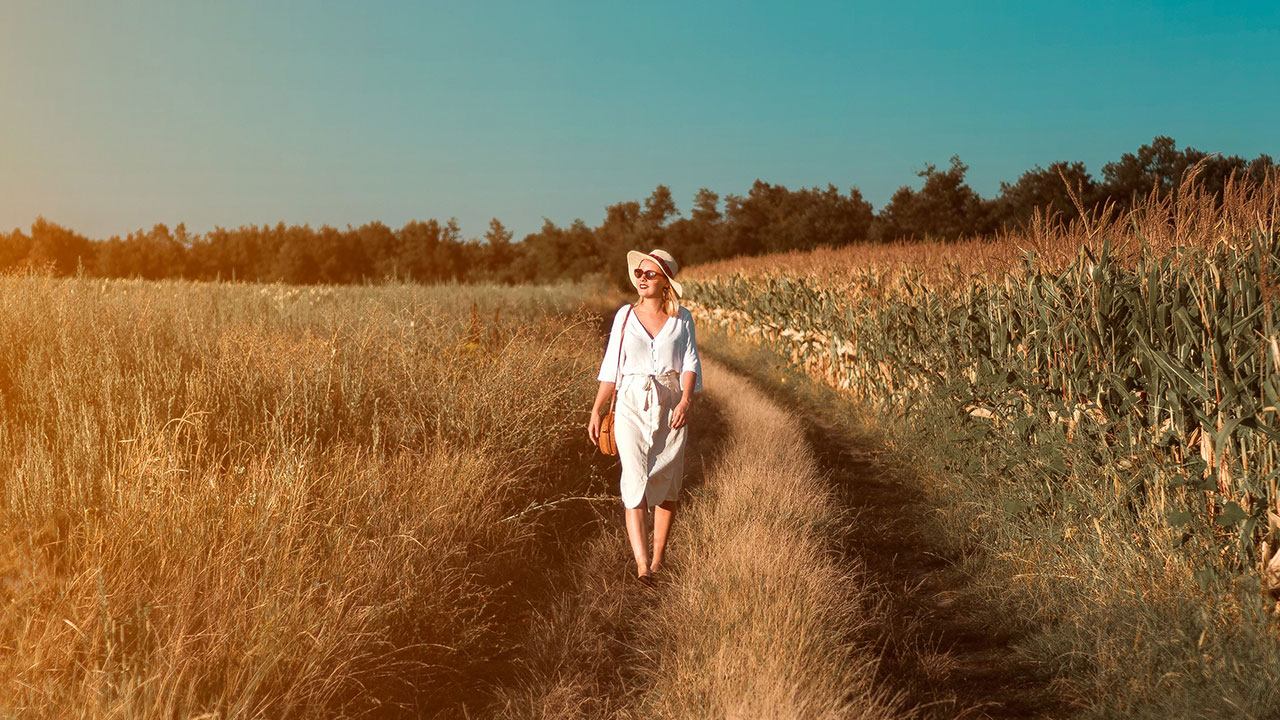 A elder woman walking on the corn field